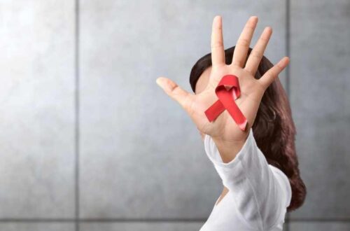 Mano con lazo rojo, símbolo de conciencia y prevención del VIH y decisiones de cuidado