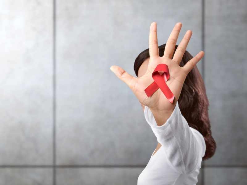 Mano con lazo rojo, símbolo de conciencia y prevención del VIH y decisiones de cuidado