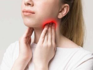 mujer tocándose la zona en dónde se encuentra la glándula tiroidea, pensando que puede ser la que desata su caída del cabello 